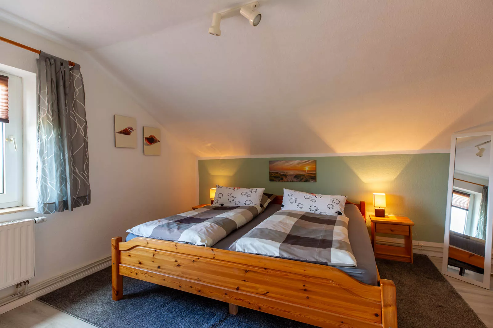 Gemütliches Schlafzimmer mit Doppelbett aus hellem Kiefernholz und frisch bezogener Bettwäsche in der Ferienwohnung Radmokerhus auf der Nordseeinsel Pellworm