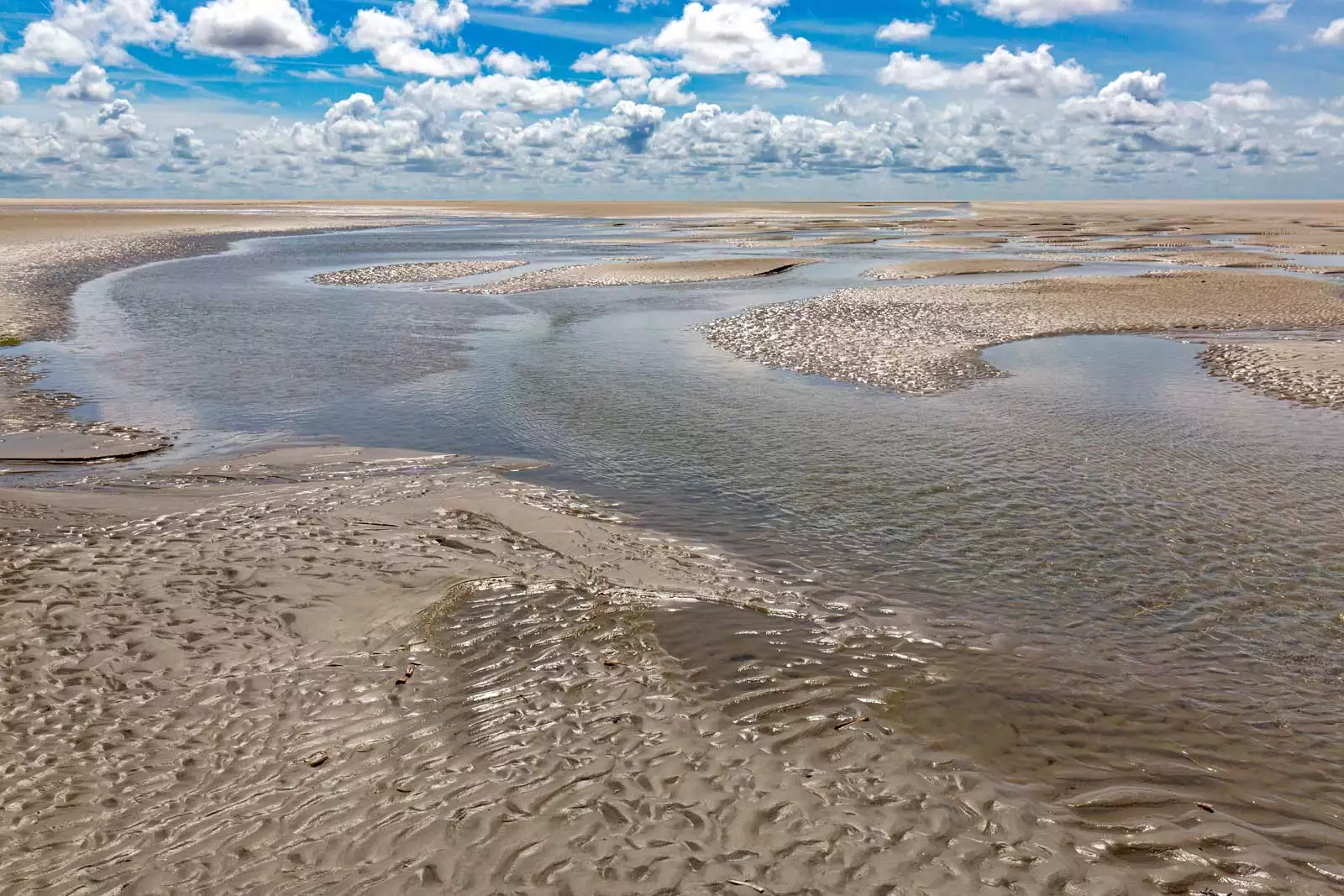 Wattenmeer bei Ebbe auf Pellworm mit weitem Himmel und sichtbaren Prielen